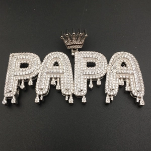 Macro shot of silver hip hop PAPA pendant with crown detail and dripping letter design