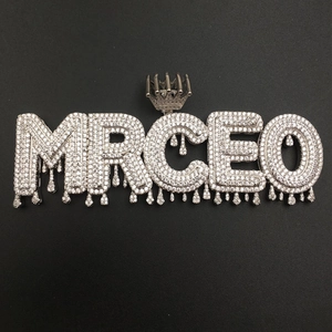 Macro view of iced out MRCEO letter pendant with crown bail and dripping metal design