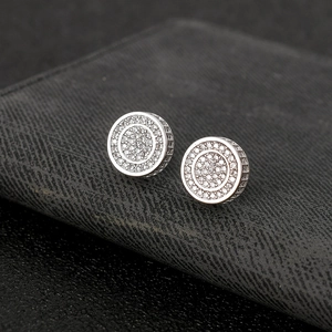 Macro shot of silver round hip hop stud earrings with micro-pave zircons on black leather