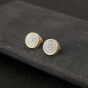 Macro shot of gold hip-hop stud earrings with micro-paved zircons on black leather