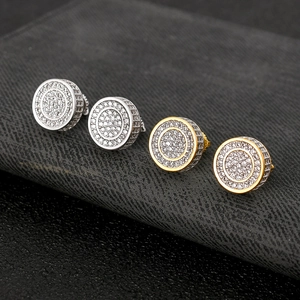 Macro view of gold and silver round stud earrings with pave-set zircons on dark leather