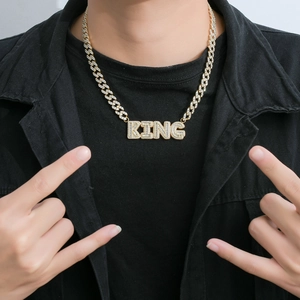 Close-up of golden Cuban link necklace with iced-out KING pendant on a male model