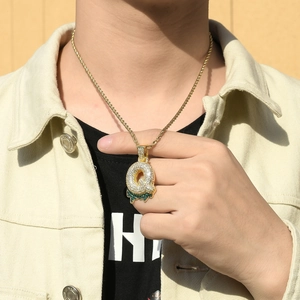 Detailed view of large gold plated bubble letter pendant with green and white zircons