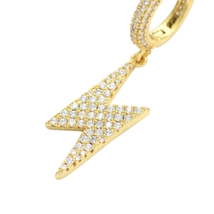 Vue macro de boucles d'oreilles créoles dorées avec pendentifs éclair et zircons micro-pavés