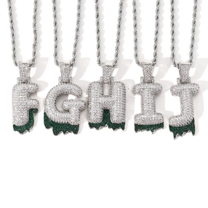 Macro shot of silver hip hop bubble letters F to J with green zircon accents and rope chain