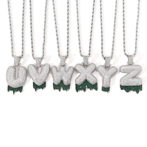 Detail of hip hop iced out bubble letters with green drip design and rope chain necklace