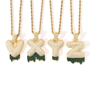 Macro detail of iced-out bubble letter pendants with green drip effect and rope chain