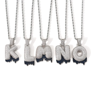Macro view of iced out bubble letters with blue dripping stones and silver rope chain
