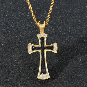 Close-up of black stone paved cross pendant with gold border and sparkling twist chain