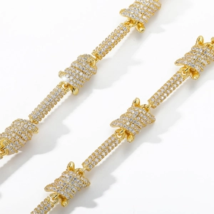 Macro shot of gold-plated hip hop chain featuring barbed wire links and pave set zircons