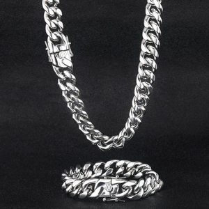 Macro view of silver stainless steel Cuban chain necklace and bracelet set with round clasp