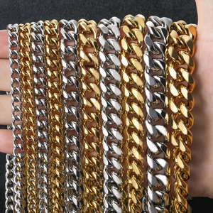 Detail of diverse cuban link chains in gold and silver finish on hand with black background