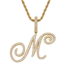 Macro detail of gold plated letter M pendant with iced out cubic zirconia stones