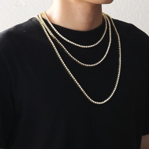 Close-up of triple layered gold tennis chains with round-cut sparkling zircons on black tee