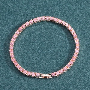 Rose gold tennis bracelet with pink rhinestones displayed on a textured green background