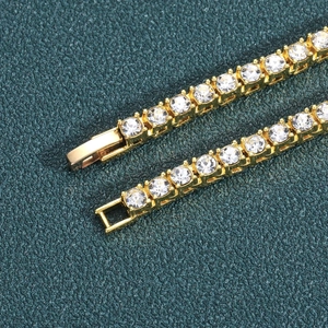 Macro detail of gold-plated tennis chain featuring prong-set clear cubic zirconia crystals