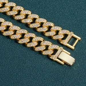 Gros plan d'un bracelet gourmette doré serti de cristaux avec un fermoir à boîte sécurisé