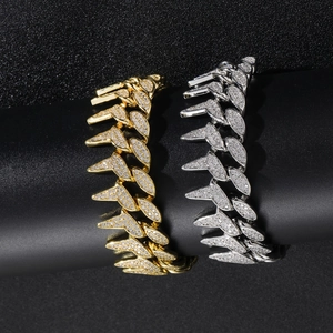 Macro shot of gold and silver spiked Cuban bracelets with white pave-set zircons