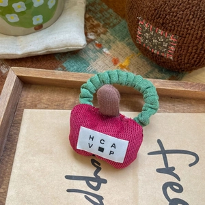 Vue détaillée d'un chouchou en peluche en forme de pomme avec un élastique vert