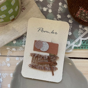 Détail de pinces à cheveux à nœud marron sur carte beige avec décor rétro élégant