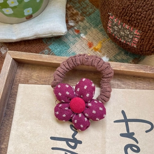 Détail de l'élastique à cheveux marron fait main avec fleur en tissu violet et centre rouge