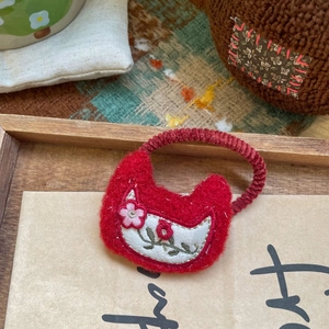 Gros plan d'un chouchou en feutre rouge fait main avec des broderies de fleurs fines