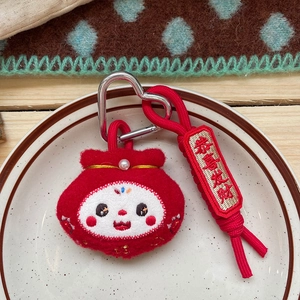 Detailed macro view of a red plush lucky bag keychain with a golden pearl and embroidery