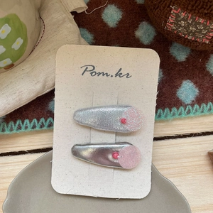 Close-up of glittery silver floral hair clips with pink pearls on presentation card