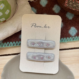 Detail of silver glitter flower hair clips with pink rhinestones on premium card display