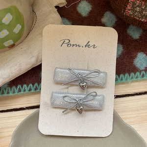 Detail of silver glitter flower hair clips with heart charms on beige paper card