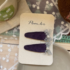 Gros plan sur des barrettes en velours violet avec nœuds en dentelle et perles