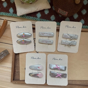 Five pairs of elegant silver bow hair clips with pearls and rhinestones on card display