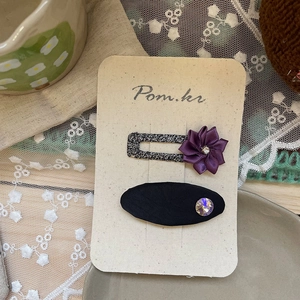 Détail des barrettes à fleurs en satin violet et strass faites main sur carton
