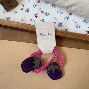 Detailed view of handmade eggplant hair ties with pink spiral ropes and felt charms