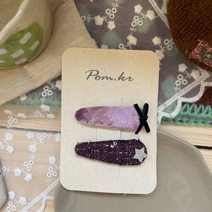 Détail de barrettes à cheveux en velours et tweed violets avec nœud et étoile sur carte