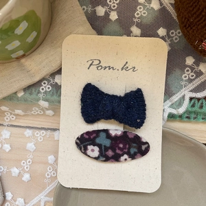 Détail de barrettes en tissu floral violet et nœuds bleu marine sur carte de présentation