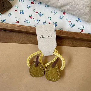 Detail view of pear-shaped felt hair tie with yellow elastic on a rustic fabric background