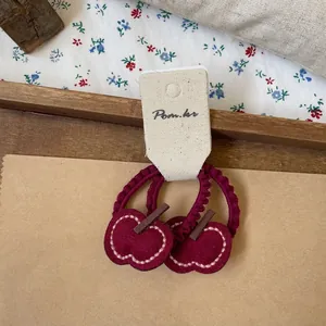 Detail of red apple felt hair ties with wavy elastic bands on vintage texture background