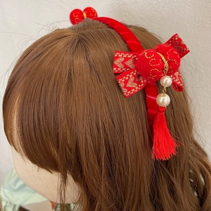 Detail van rode fluwelen haarband met gouden strik, witte parels en rode kwastjes
