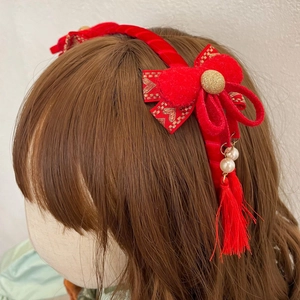 Detail van rode fluwelen haarband met strik, parels en lange kwastjes in Chinese stijl