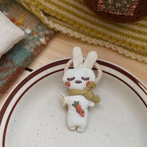 Gros plan d'un chouchou lapin en tissu blanc fait main avec broderie carotte sur une assiette