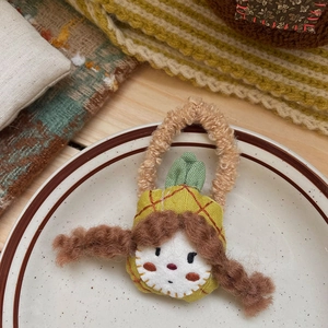 Détail d'un élastique poupée fait main avec chapeau ananas sur assiette blanche