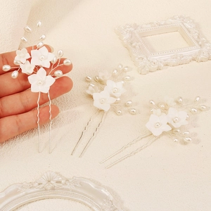 Detailed close-up of three white flower hair pins with pearls for bridal hairstyles