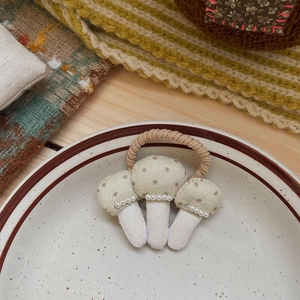 Détail d'élastique à cheveux champignons en tissu avec perles sur une assiette rétro