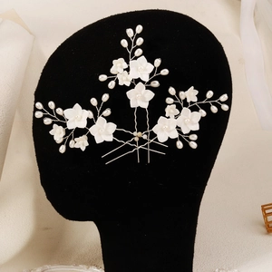 Handmade bridal hair pins set with white flowers and pearls on a black mannequin