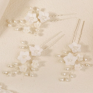 Detailed close-up of three U-shaped bridal hair pins with white flowers and pearls