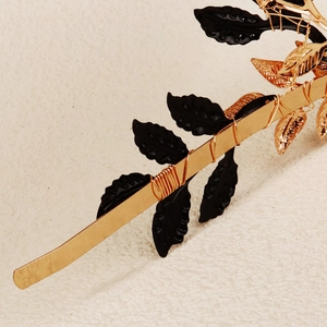 Detailed close-up of handmade gold and black leaf headband with intricate wire wrapping