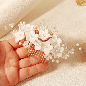 Close-up of handmade bridal hair comb with white flowers, pearls and golden wire details
