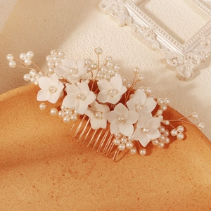 Macro view of vintage white floral bridal hair comb with pearls and golden metal tines