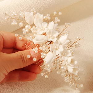 Close-up of handmade white resin flowers and pearls on champagne gold bridal hair comb
